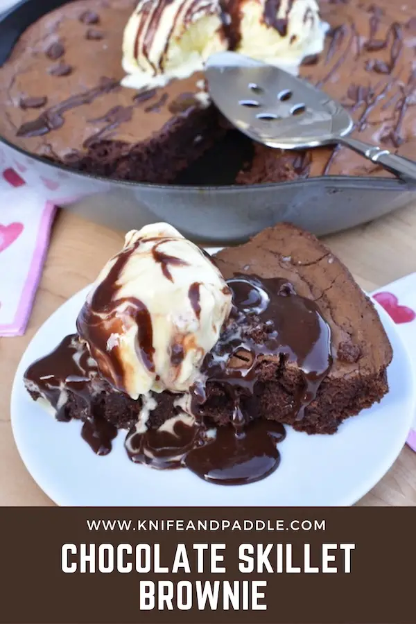Slice of chocolate skillet brownie topped with vanilla ice cream and hot fudge