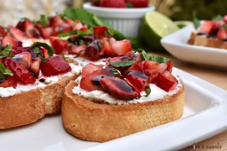 Strawberry-Goat Cheese Crostini on a plate topped with fresh mint and balsamic glaze