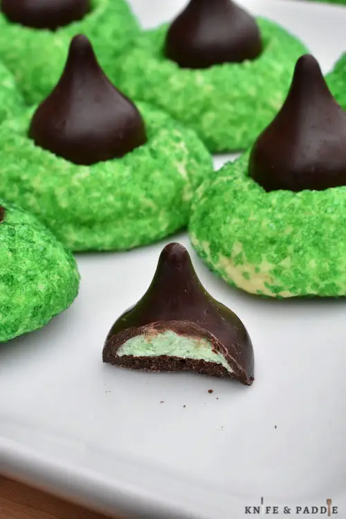 Hershey's Kisses Mint Truffles atop a green sugar cookie on a plate