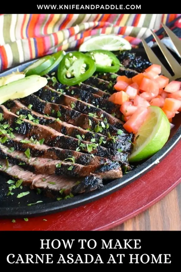 Carne asada on a plate with jalapeños, chopped tomatoes, lime and avocados