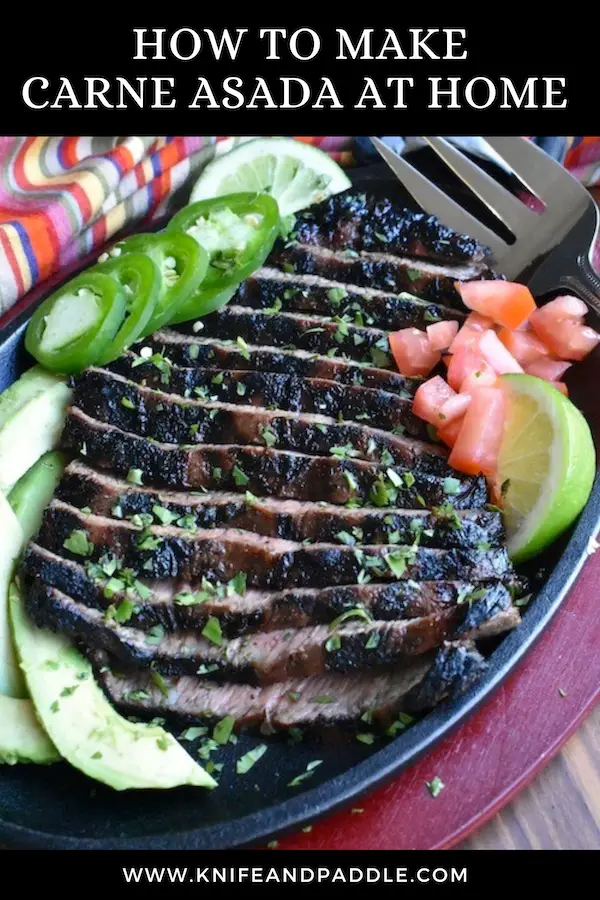 Carne asada on a plate with jalapeños, chopped tomatoes, lime and avocados