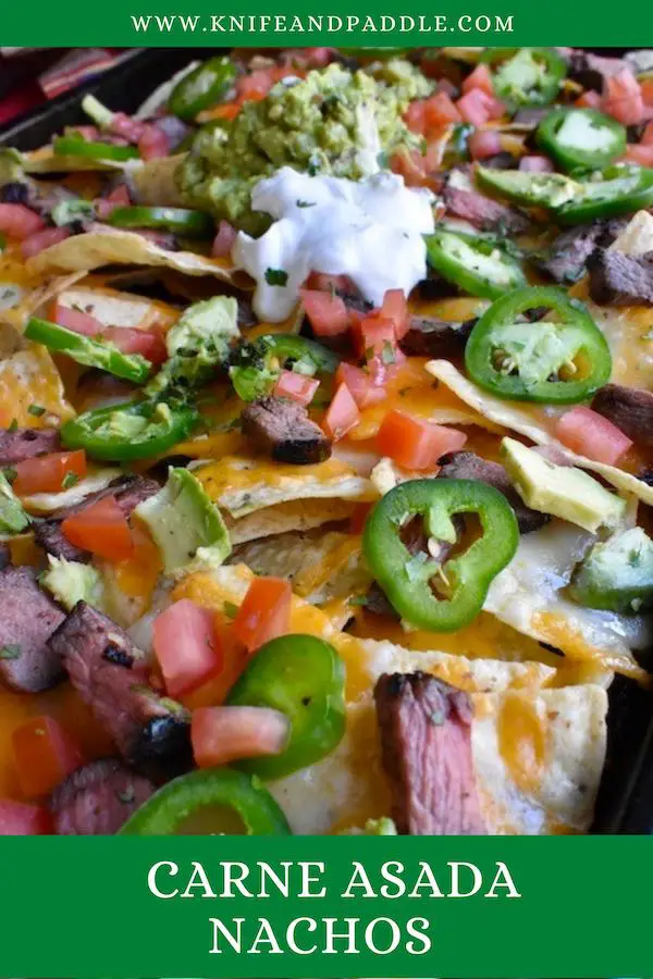 Tortilla chips, melted cheeses, flat iron steak pieces, jalapeños, diced tomatoes, avocados in a sheet pan topped with sour cream and guacamole