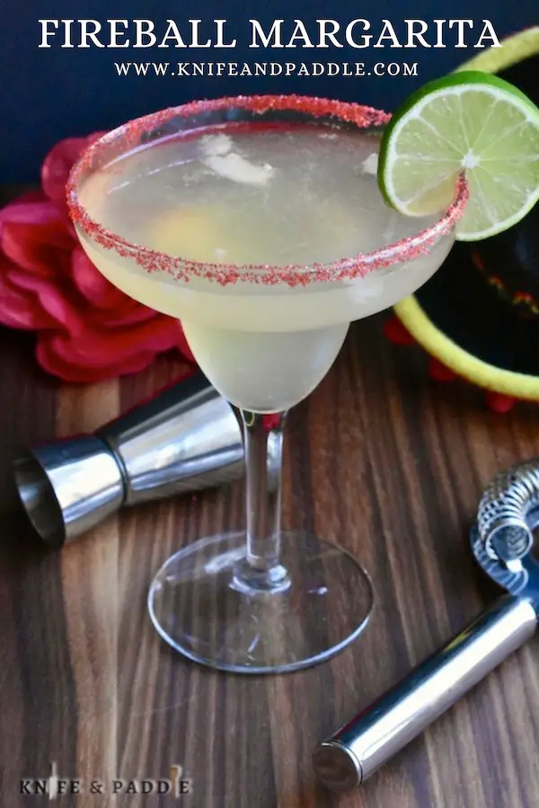 Simple syrup, Milagro, Cinnamon Whiskey, lime juice and Cointreau mixed and poured into a glass with a red sparkling sugar rim garnished with a lime slice 