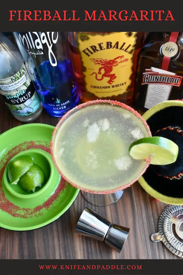 Simple syrup, Milagro tequila, Fireball Cinnamon Whiskey, lime juice and Cointreau mixed and poured into a glass with a red sparkling sugar rim garnished with a lime slice 