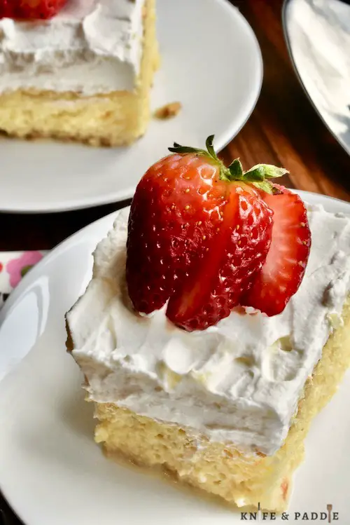 Tres Leches Cake with whipped cream frosting and topped with a strawberry