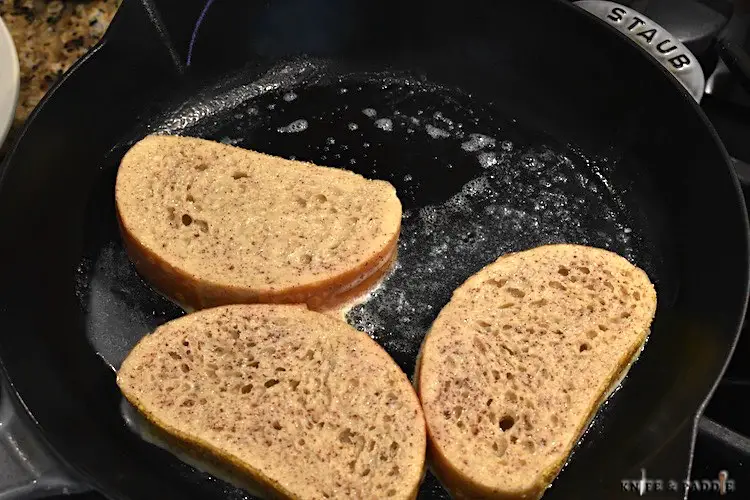 Bread slices dipped in a custard mixture cooking in melted butter on a skillet