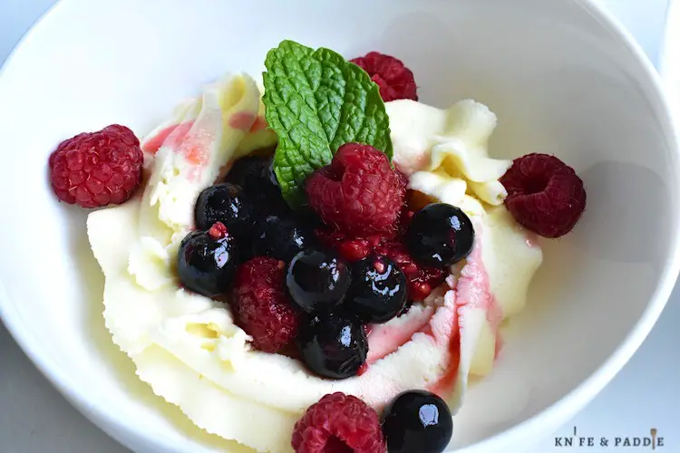 Mascarpone Berry Bowl with fresh raspberries and blueberries, topped with a sprig of mint 