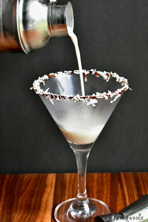 Coconut Rum, Creme de Cacao, Amaretto and heavy cream shaken until cold and strained in a glass rimmed with chocolate syrup and shredded coconut