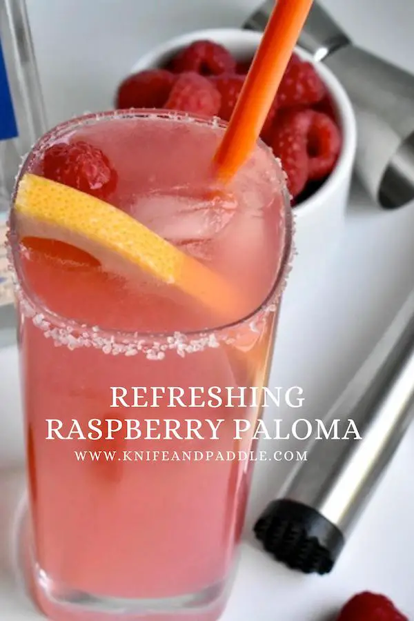 Refreshing Raspberry Paloma with a salted rim and garnished with a grapefruit slice and raspberry served in a high ball glass with ice