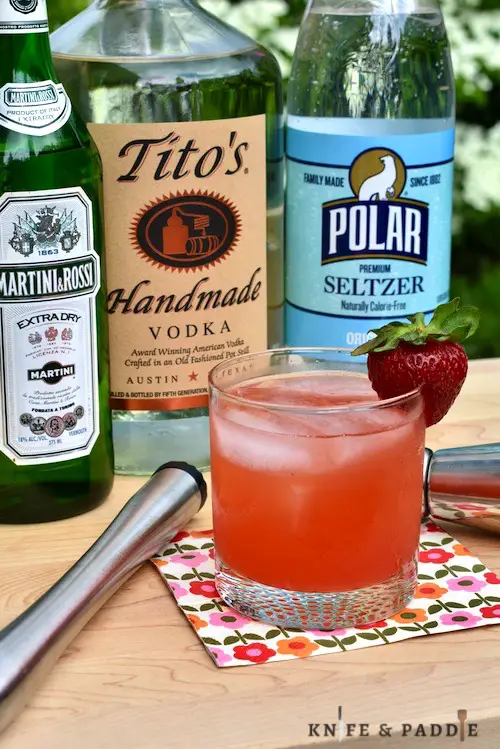Vermouth, Tito's and Seltzer mixed up with rhubarb simple syrup and muddled strawberries