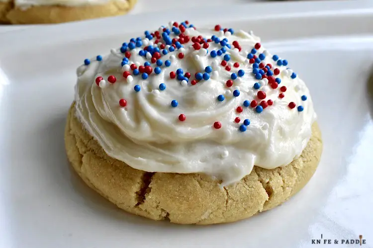 Vanilla buttercream frosted treat with red, white and blue sprinkles on a plate