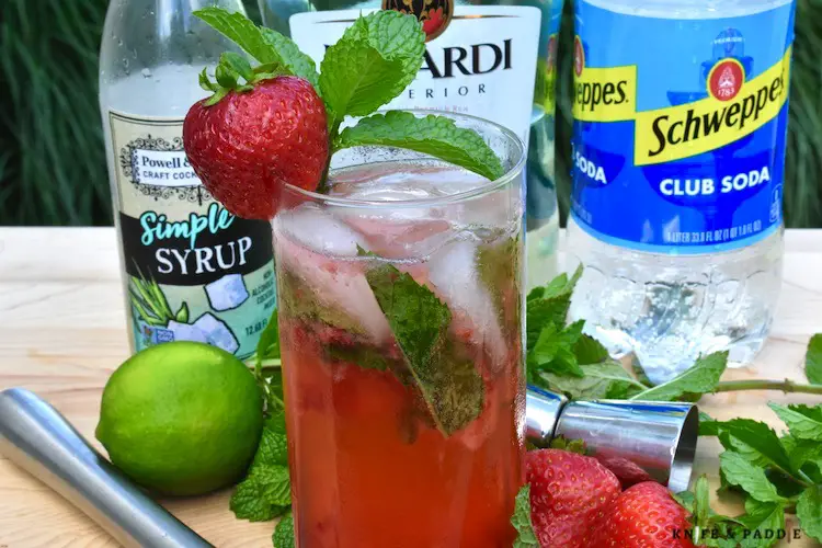 Simple syrup, Bacardi Rum, strawberries, club soda, lime juice, mint and ice combined in a highball glass garnished with a fresh mint sprig and strawberry