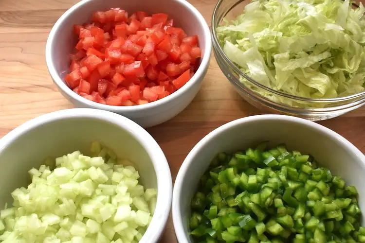 The best taco dip ingredients:  chopped tomatoes, shredded lettuce, chopped cucumbers and chopped green peppers