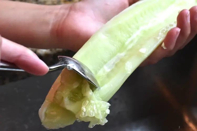 Scooping the seeds out of a cucumber with a spoon