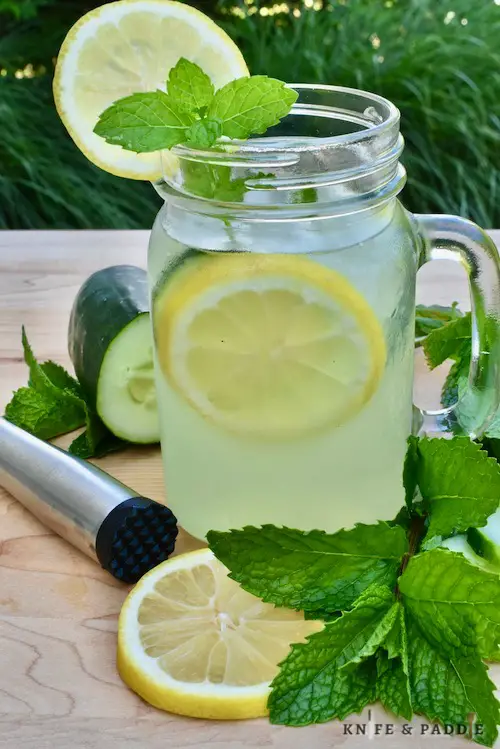 Vodka, cucumber, mint, lemonade, elderflower liqueur and ice mixed together in a mason jar and served with a cucumber and lemon wheel and a fresh mint sprig