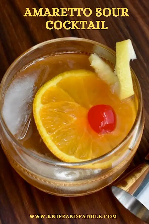 Italian Cocktail with a nutty libation, citrus and simple sugar in a rocks glass with ice garnished with a lemon twist, orange slice and maraschino cherry