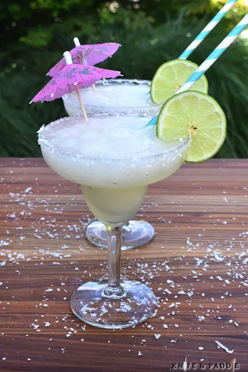 Frozen Coconut Margaritas with a coconut-salt rim, lime wheel and a cocktail umbrella