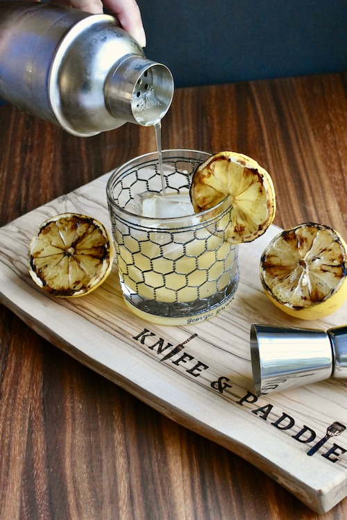 Smokey Citrus Cocktail being poured into a rocks glass 