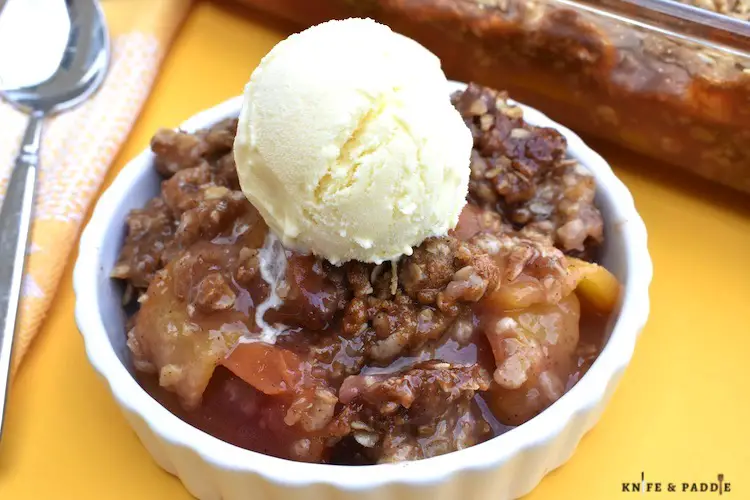 Delicious Summer Dessert in a bowl with fruit and a brown sugar oat topping and a scoop of vanilla ice cream 