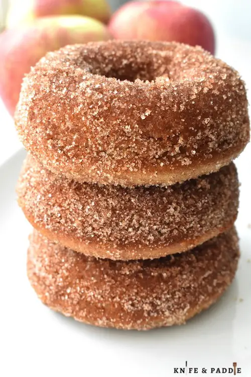 Baked Apple Cider Donuts stacked with cinnamon-sugar topping on a plate