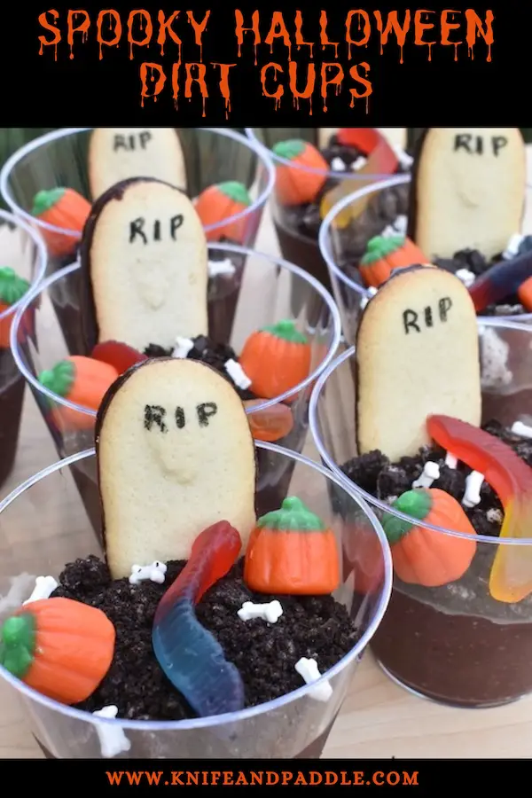 Graveyard treats with chocolate Jello, crushed Oreos, candy pumpkins, candy bones, gummy worms and a RIP tombstone Milano cookie