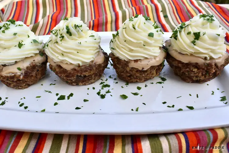 Mini Meatloaf Cupcakes with mashed potato "frosting" and a sprinkle of parsley on a plate