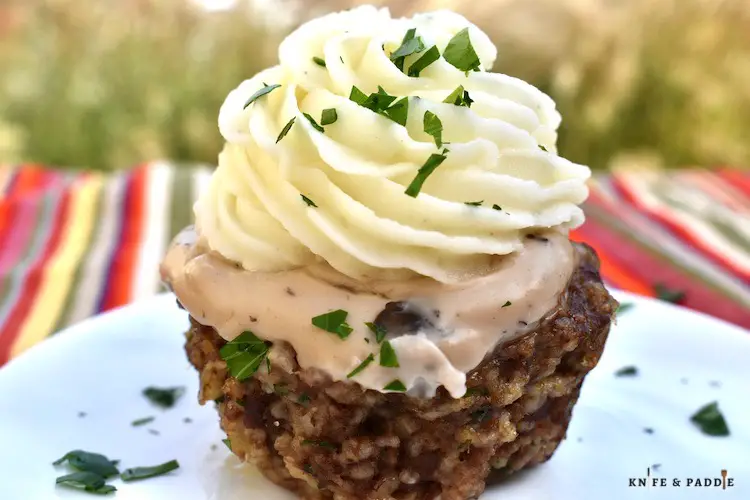 Mini Meatloaf Cupcakes with mashed potato "frosting" and a sprinkle of parsley on a plate
