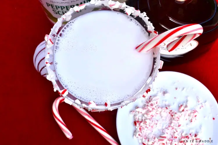 White Chocolate Peppermint Martini with a marshmallow dipped rim and candy cane coating and a candy cane for garnish