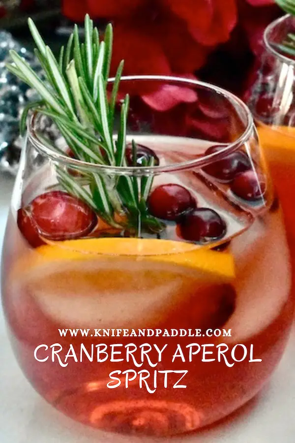 Festive Winter Cranberry Aperol Spritz garnished with cranberries, orange slice and a rosemary sprig