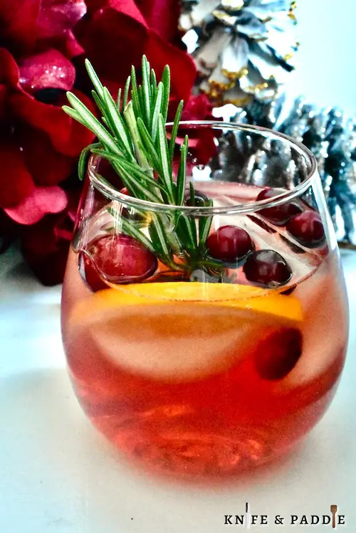 Festive Winter Cranberry Aperol Spritz garnished with cranberries, orange slice and a rosemary sprig