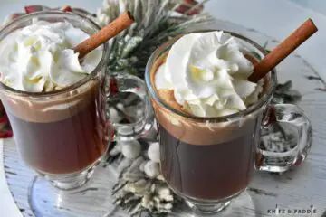 Hot Buttered Rum Cocktail with whipped cream and a cinnamon stick for garnish