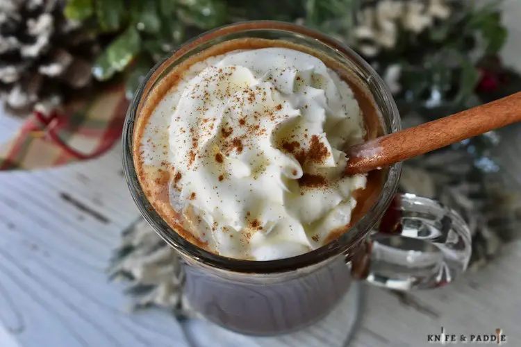 Festive Warm Winter Cocktail with whipped cream and a cinnamon stick for garnish