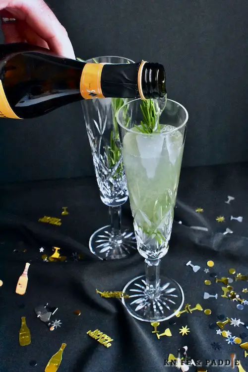 St. Germain Champagne Cocktail poured into a flute and garnished with a rosemary sprig