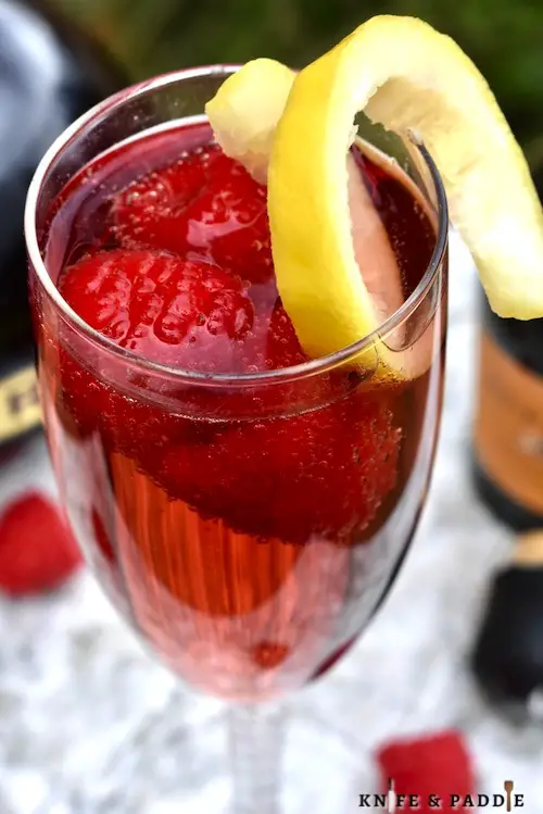 Chambord and Champagne Cocktail topped with fresh raspberries and a lemon twist