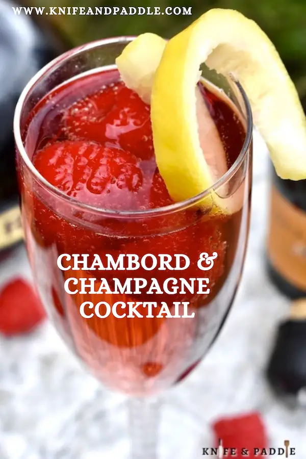 Vibrant red holiday cocktail made with raspberry liqueur and Prosecco and topped off with fresh raspberries and a lemon twist for garnish