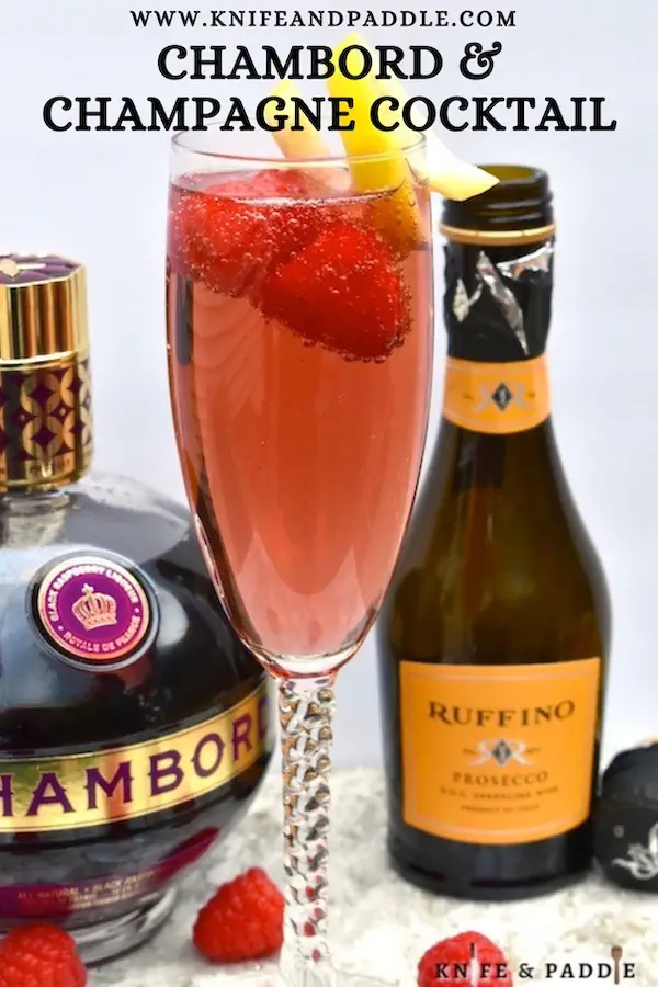 Vibrant red holiday cocktail made with raspberry liqueur and Prosecco and topped off with fresh raspberries and a lemon twist for garnish
