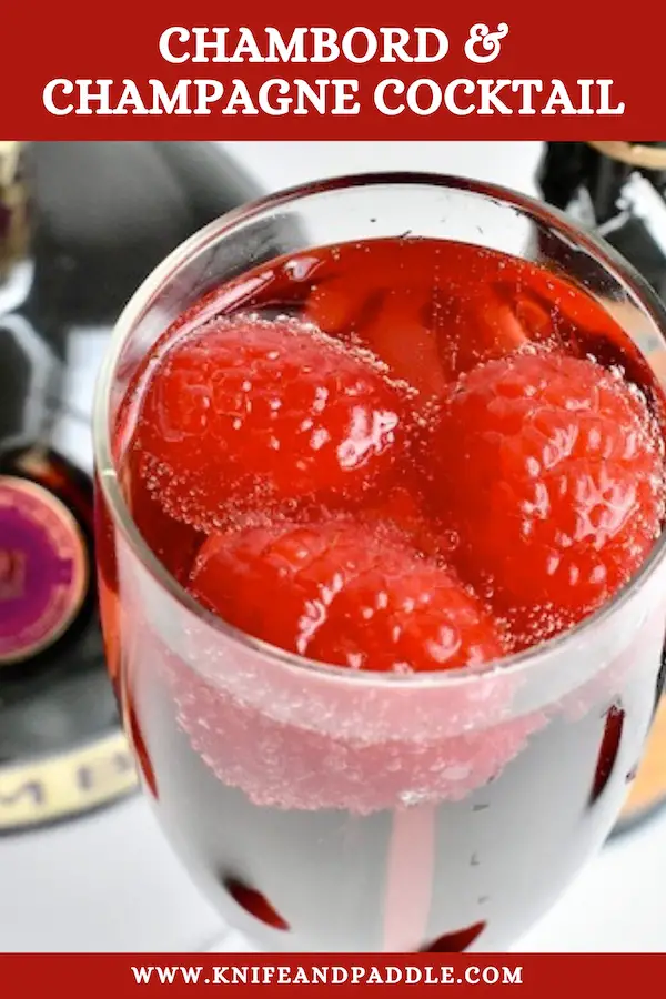 Vibrant red holiday cocktail made with raspberry liqueur and Prosecco and topped off with fresh raspberries 