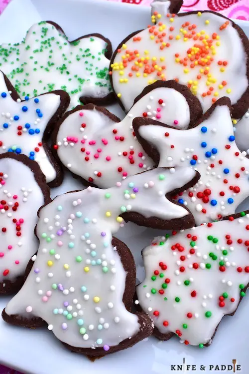 Holiday cookies on a plate with vanilla frosting and holiday nonpareils 