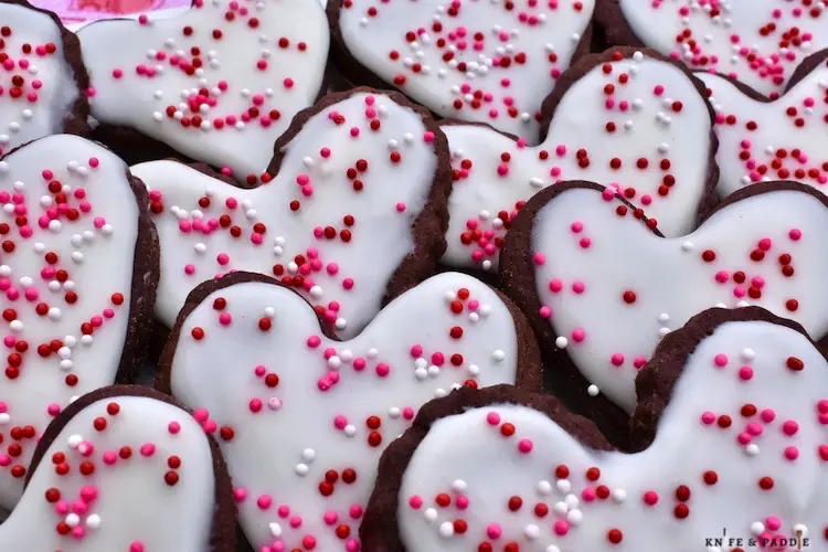 Chocolate Cutout Sugar Cookies heart shaped with vanilla frosting and red, white and pink nonpareils 