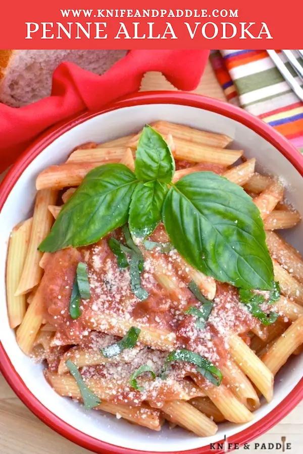Pasta in a bowl topped with a rich tomato cream sauce, fresh basil and parmesan cheese