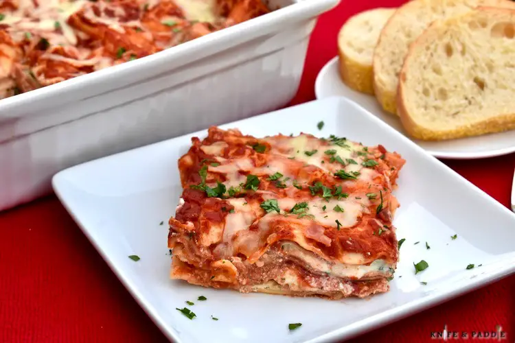 Quick Homemade Lasagna in a baking dish, on a plate sprinkled with fresh parsley and slices of Italian bread