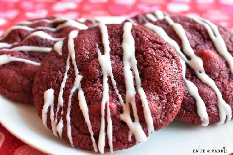 Red Velvet White Chocolate Chip Cookies with white chocolate drizzle on a plate
