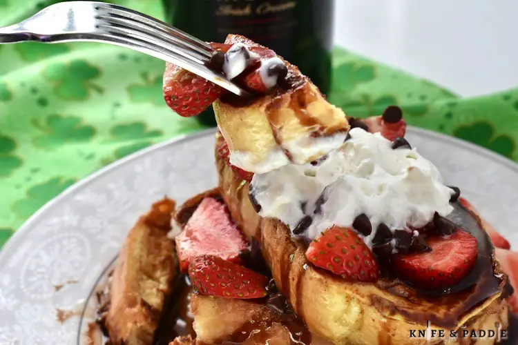 St. Patrick's Day Breakfast Recipe topped with strawberries, whipped cream, chocolate syrup, maple syrup and chocolate chips