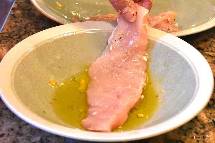 Dipping a thin chicken breast into olive oil