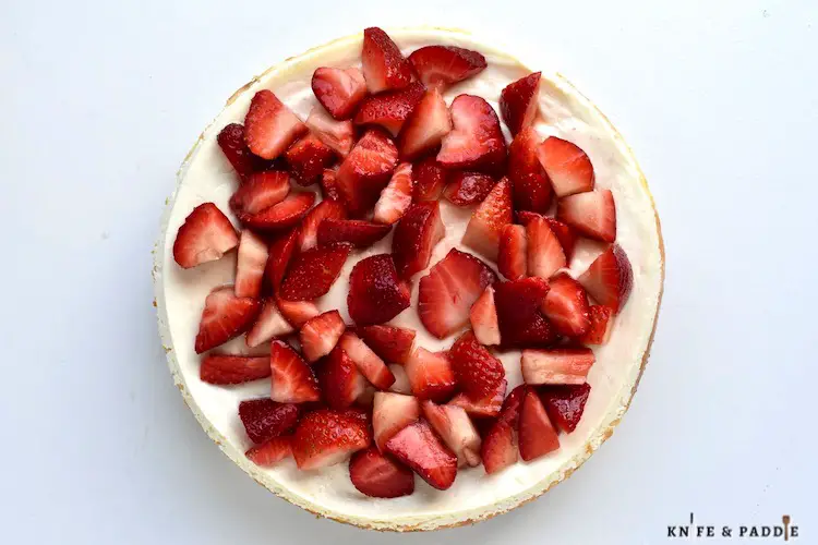 Delicious cream cheese and sour cream dessert baked in a graham cracker crust topped with fresh strawberries