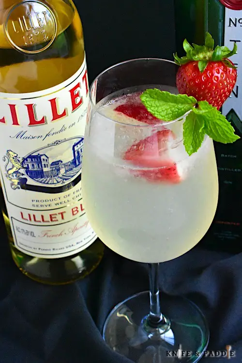 Refreshing sparkling cocktail garnished with strawberries and a mint sprig