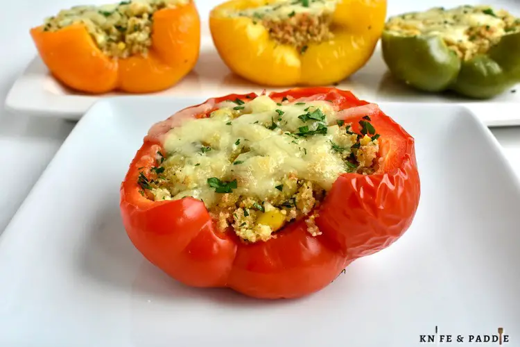 Red, yellow and green bell peppers stuffed with filling and topped with mozzarella cheese