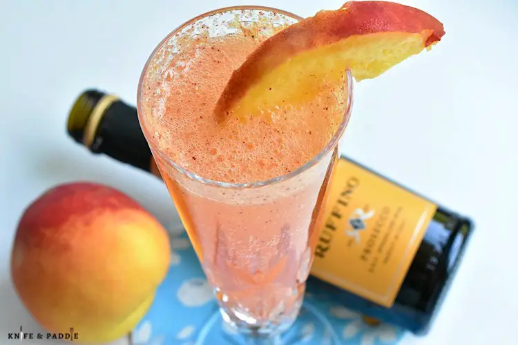 Refreshing Bellini Cocktail with a peach wedge in a Champagne glass