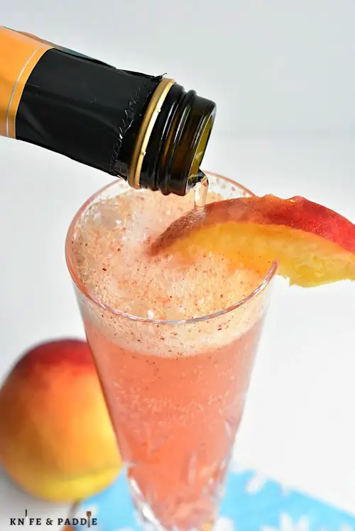 Refreshing Bellini Cocktail with a peach wedge in a Champagne glass