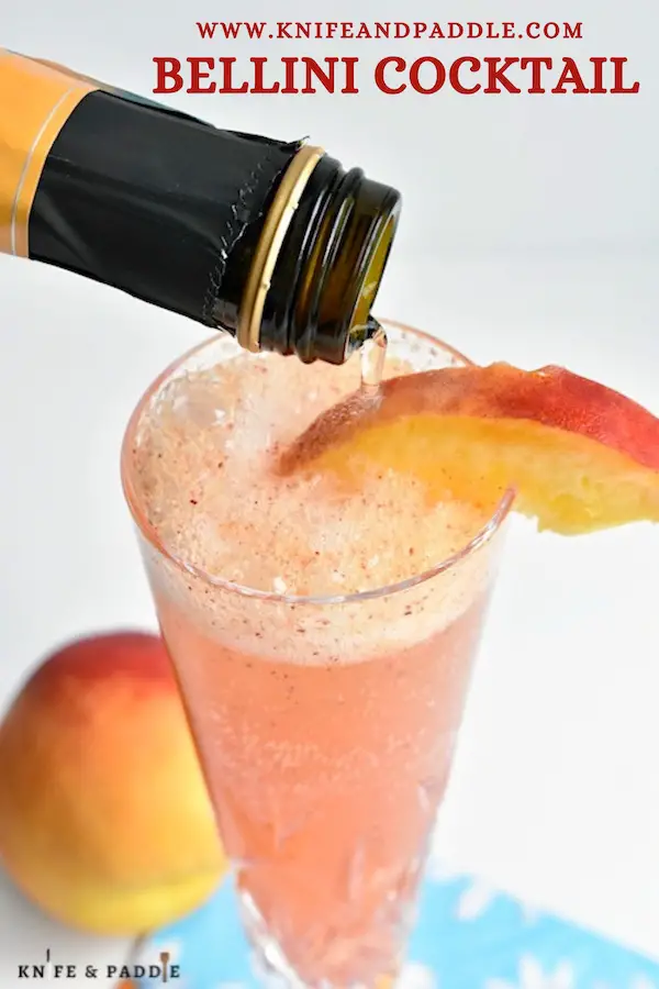 Refreshing Bellini Cocktail with a peach wedge in a Champagne glass